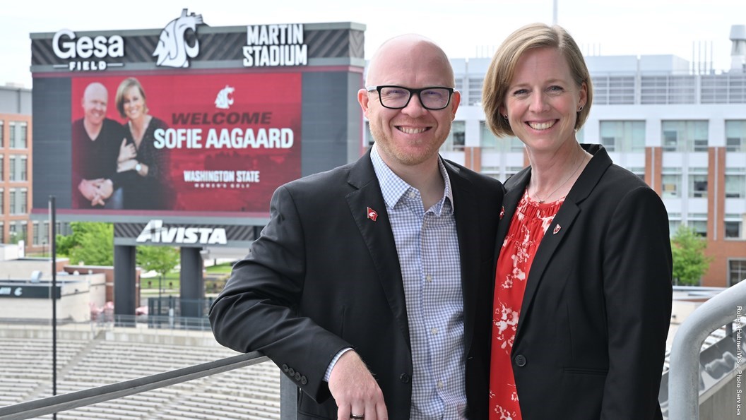 Sofia Aagaard and husband Christian standing out on the balcony of the Gesa Field Club seats in front of the videoboard with a welcome sign for coach Aagaard.