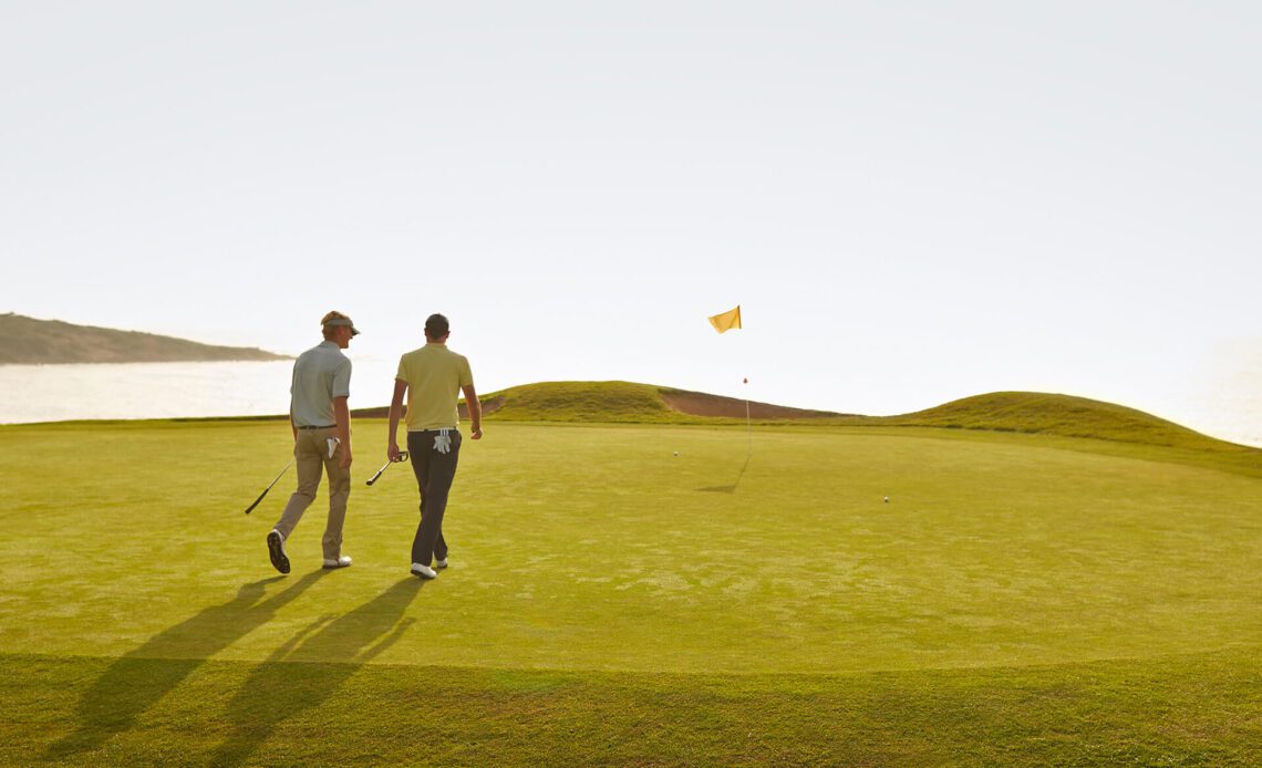 Two men walking and talking at a golf course