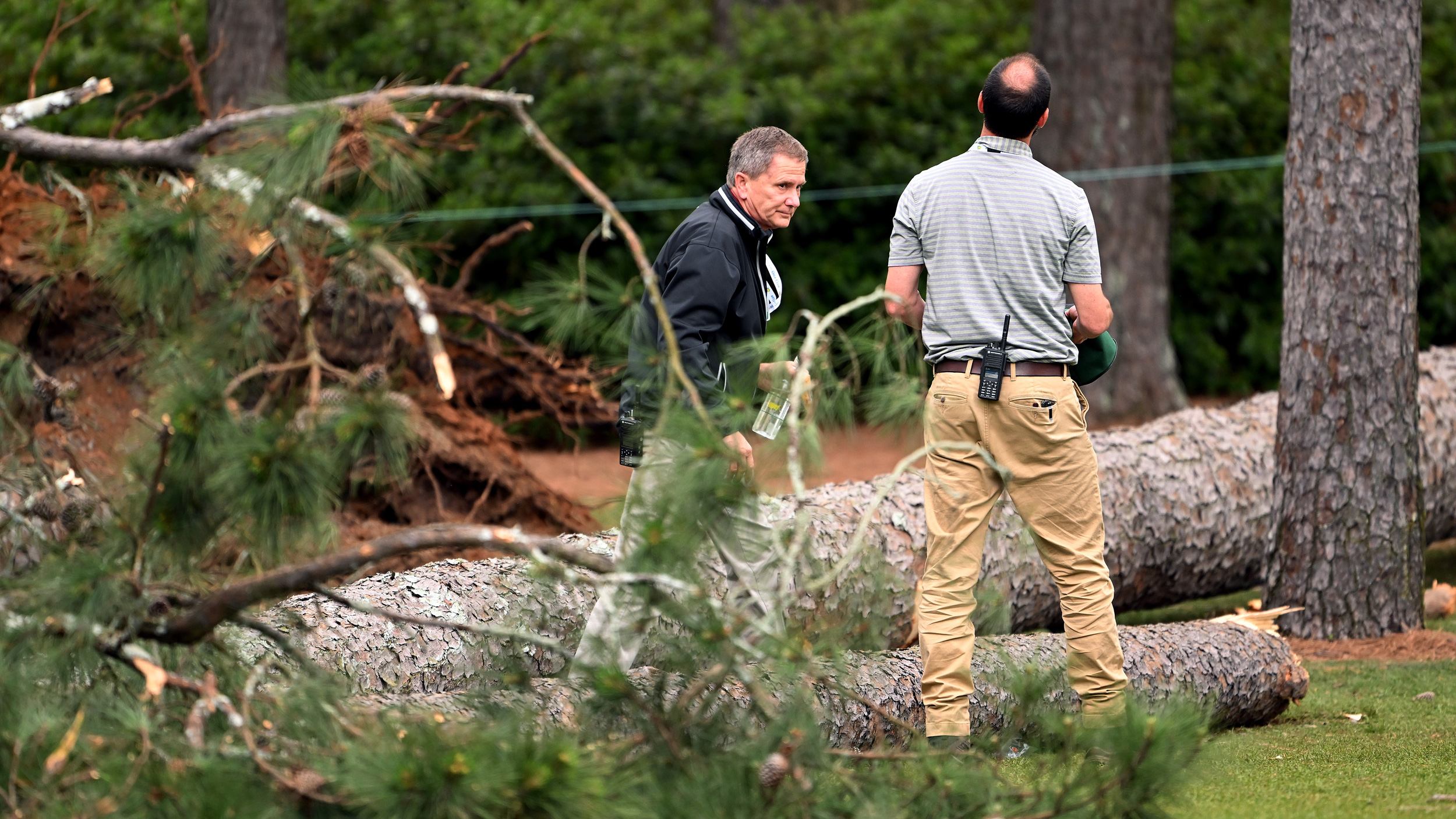 Officials look on at fallen trees at Augusta National during the 2023 Masters