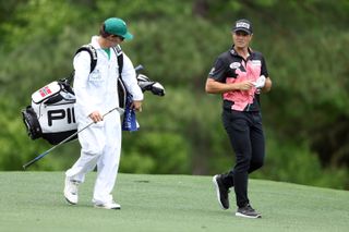 Viktor Hovland walks alongside his caddie