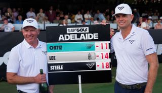 Brendan Steele and his caddie stand by a leaderboard sign