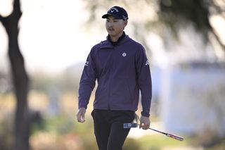 Min Woo Lee walks off the putting green holding his putter