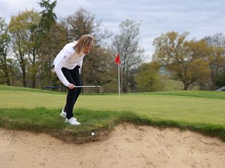 Alison Root assessing an embedded ball in the bunker face