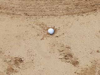 Embedded golf ball in bunker