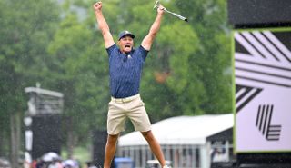 Bryson DeChambeau jumps in the air on the 18th green