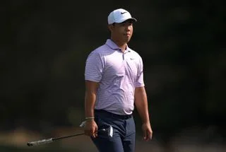 Tom Kim walks onto the putting green