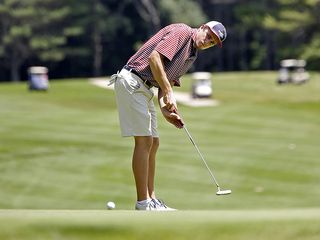 A golfer hitting a putt uphill on the green