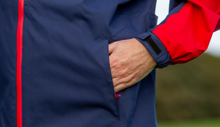 A golfer puts his hand in the Ashworth Waterproof Rain Jacket