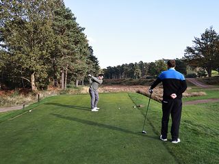 Sam De'Ath hitting a tee shot at West Hill Golf Club, in front of Nick Bonfield