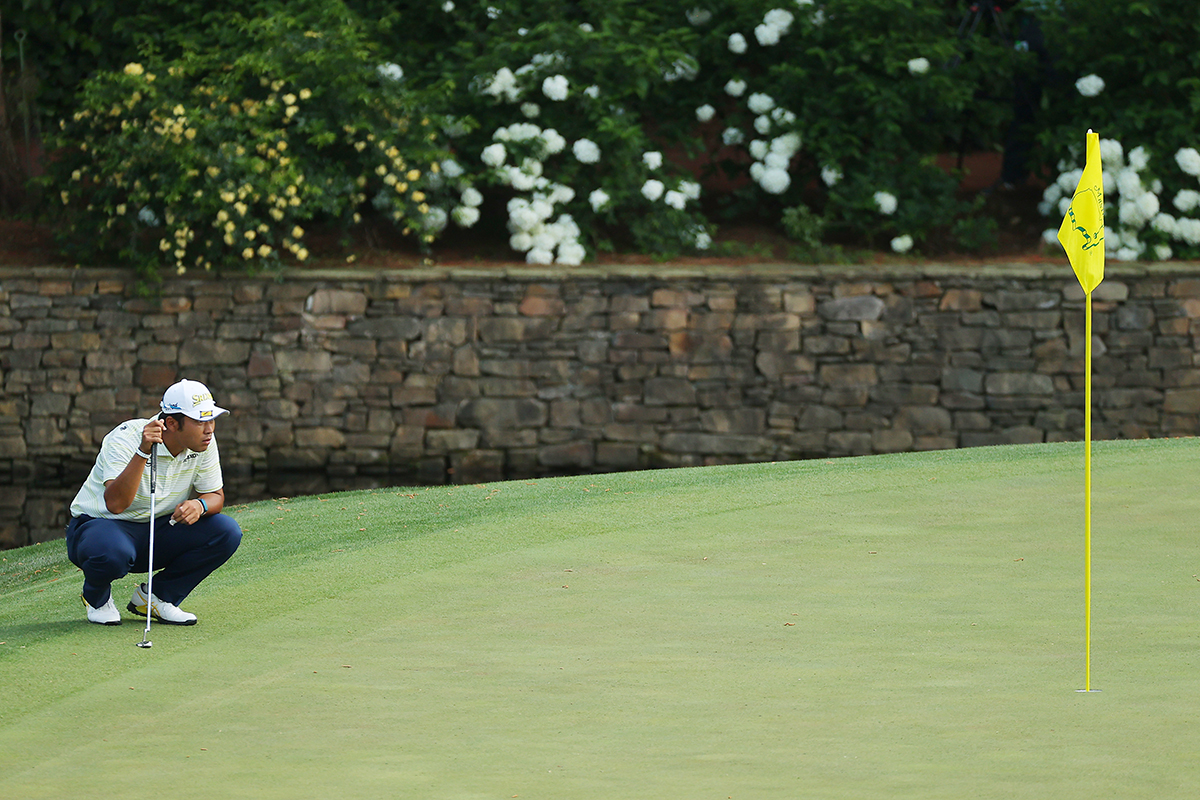 Hideki Matsuyama reading a putt on the 11th green at Augusta National on the way to winning The Masters in 2021