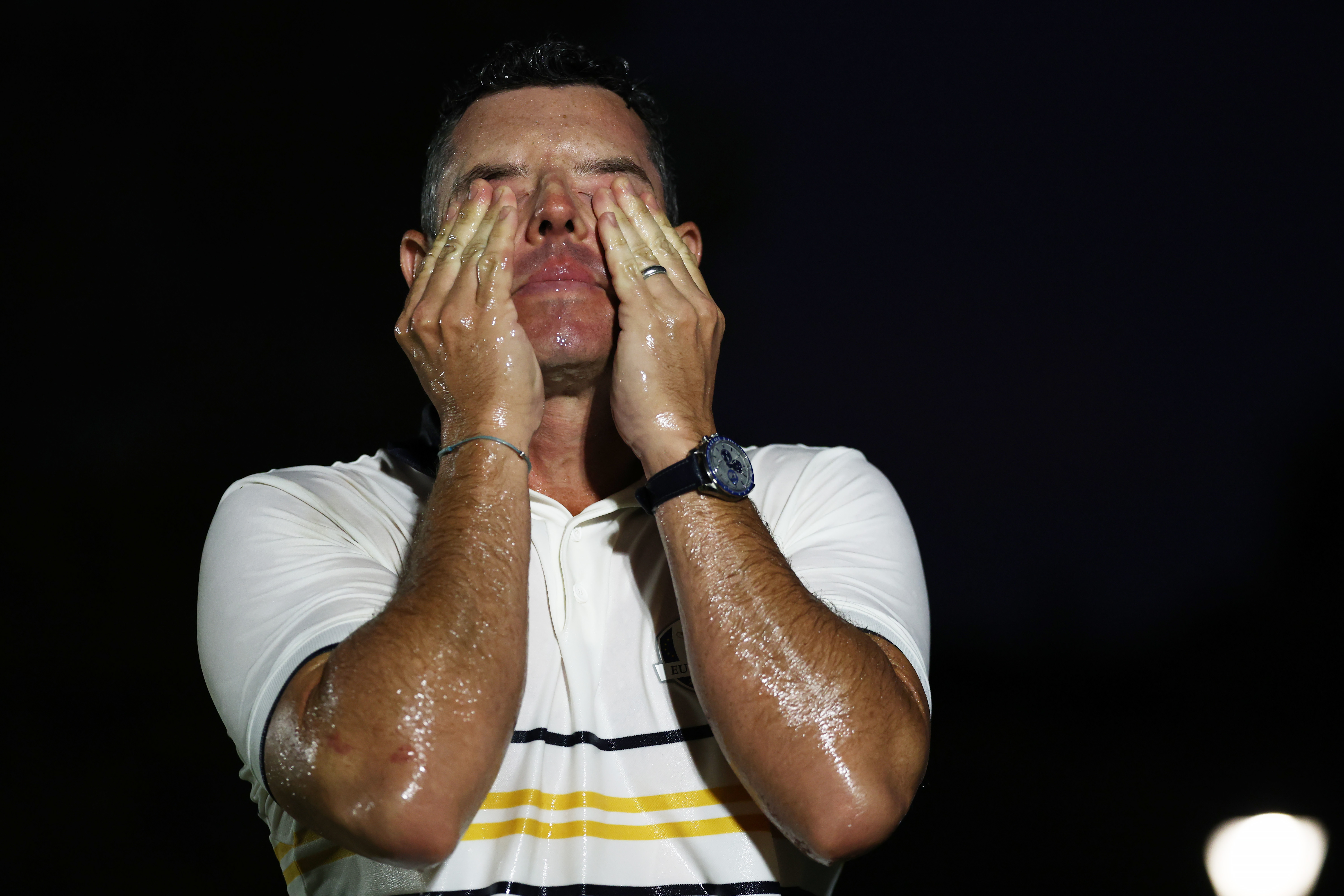 Rory McIlroy puts his hands to his face after being soaked in champagne following Team Europe's Ryder Cup win