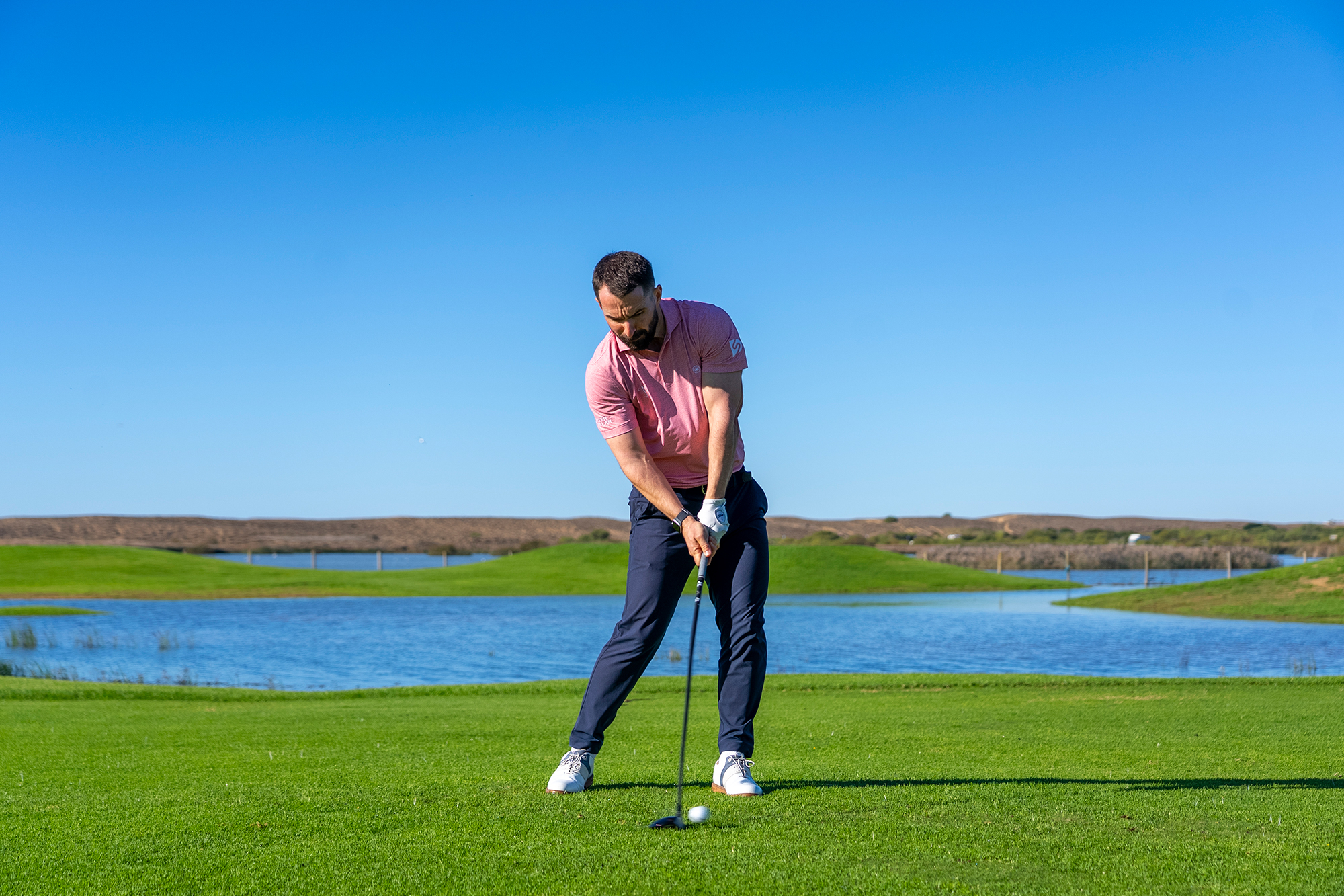 James Jankowski at impact with a fairway wood after completing the backswing and downswing, demonstrating the correct angle of attack and low point of the swing
